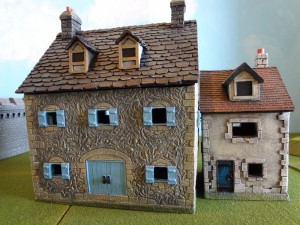 The Miniature Building Authority Stone Farm House and Stucco Town House with Dormer together outdoors.