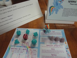 Blue dice are arranged on Savage Worlds info card with Rainbow Dash action figure