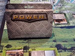 Steel box for POWER sits on playing matt with P.O.W.E.R. cards deployed to play