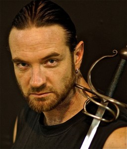 Sideburned Kyle Rowling poses with sword in headshot