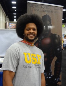 Bryan Tillman standing before a vinyl hanging at Comic-Con in San Diego promoting Dark Legacy
