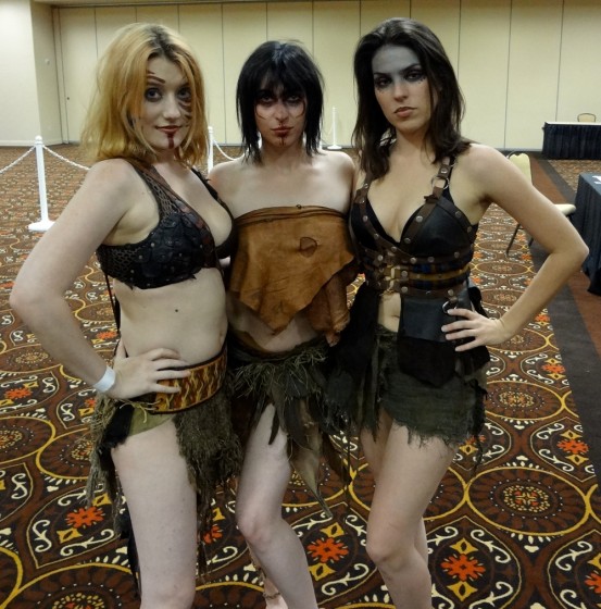 Three scantily-clad women cosplaying as barbarians in furs and leather in the Combat Con Vendors' Hall