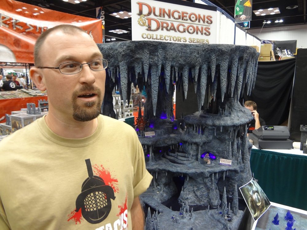 Terrain mastermind Jason Buyaki in Spartacus T-shirt Stands Before Huge Cavernous Dungeon at Gen Con