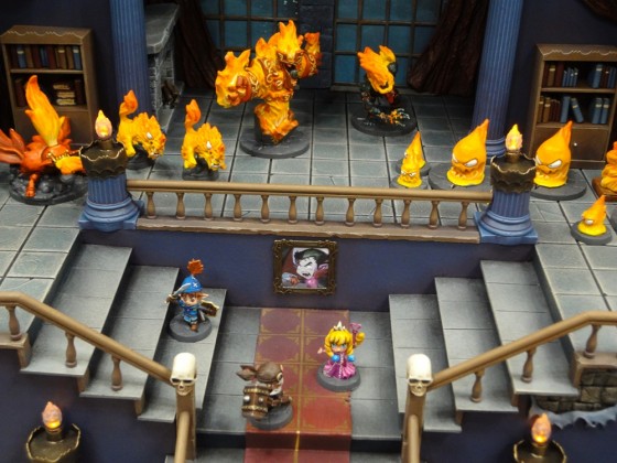 Three Cartoonish Dungeon Explorer Miniatures in Cool Mini's Super Dungeon Explore castle with fire elementals at gen con 2012