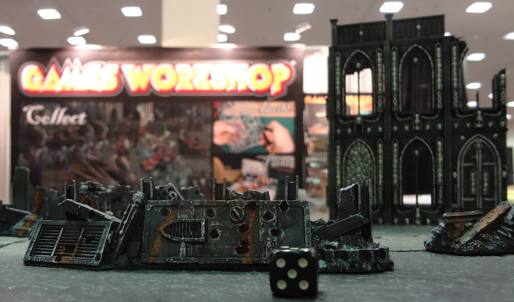 Painted miniature terrain from Cities of Death in foreground before Games Workshop banner display