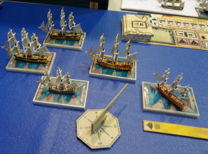 Model miniature ships battle in Sails of Glory on blue mat representing ocean
