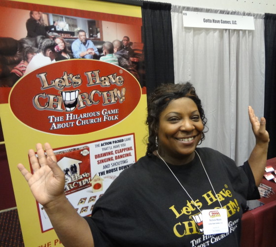 Game Designer Nichole Myers raising the roof for Let's Have Church at the GAMA Trade Show