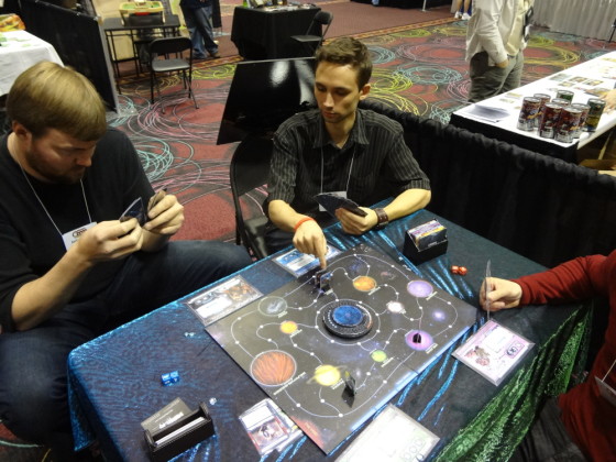 Diagonal view of board game Chaosmos with 10 planets and play pieces at GAMA Trade Show with three players