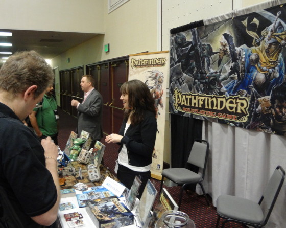 Pathfinder banner behind Jenny Bendel and Erik Mona at Paizo table in convention center