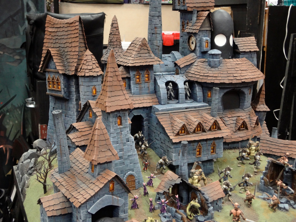 Wrath of Kings miniatures fight over a superb Goritsi city at Gen Con 2012 in front of stone buildings with red tiled roofs