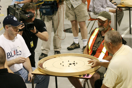 Cameraman films the 2004 World Crokinole Championship between Brian Cook and Joe Fulop as neon-vest wearing referee watches