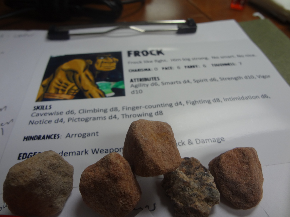 Five real rocks on top of Savage Worlds Ugh Caveman character sheet