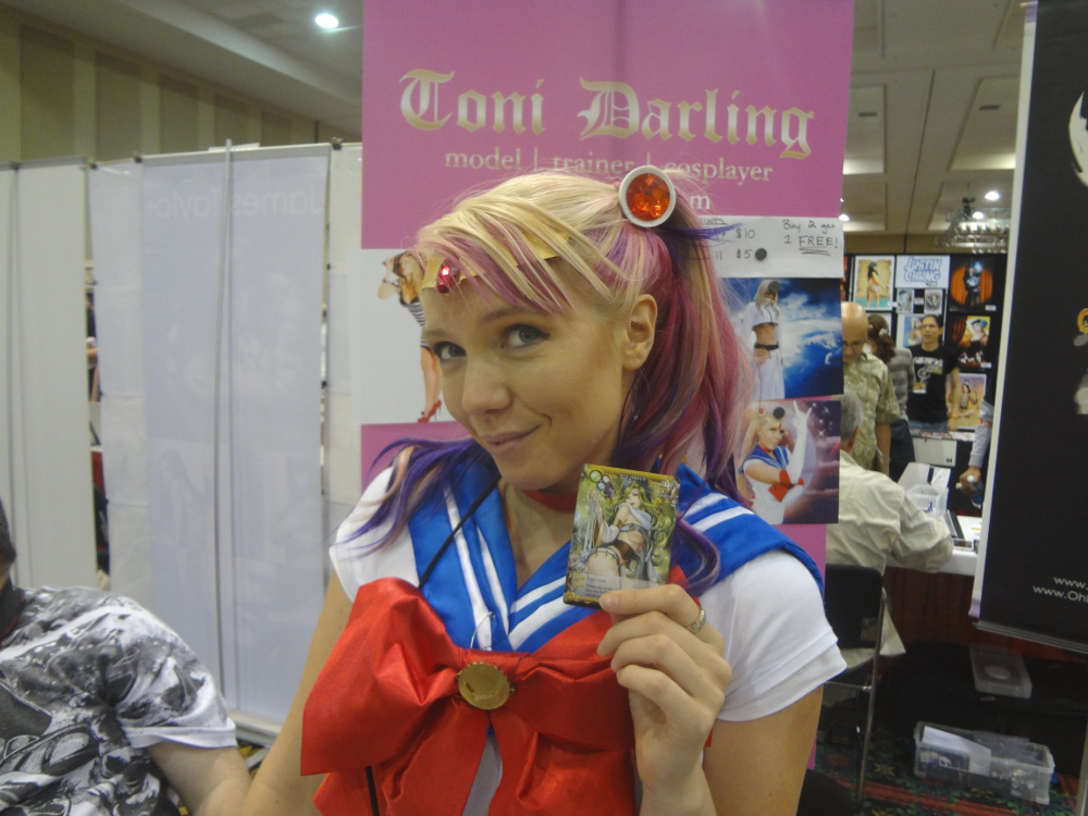 Cosplayer Toni Darling dressed as Sailor Moon holding up Kanzume Goddess Gemini card
