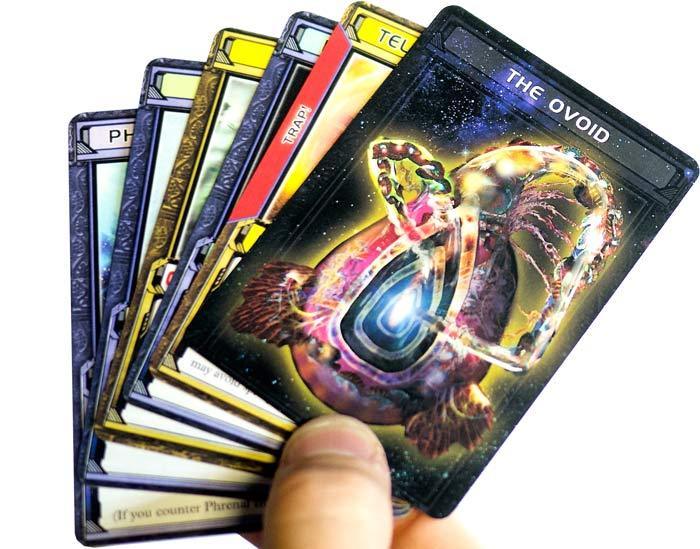 Hand of Equipment cards from board game Chaosmos with ovular Ovoid card on top